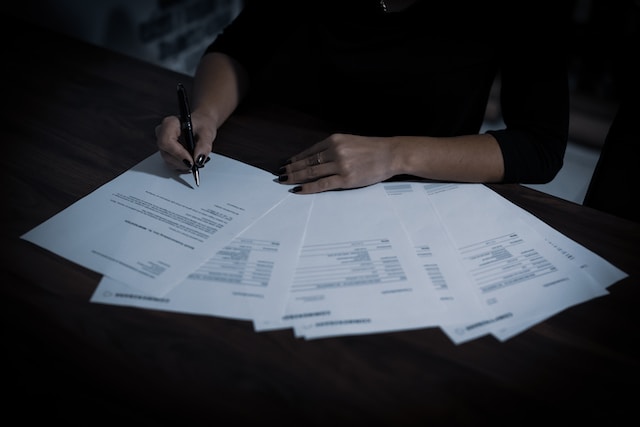 A woman sitting at a table with lots of papers.